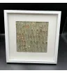 картина из серо-зелёных листьев и белых сухоцветов в белой рамке