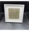картина из серо-зелёных листьев и белых сухоцветов в белой рамке
